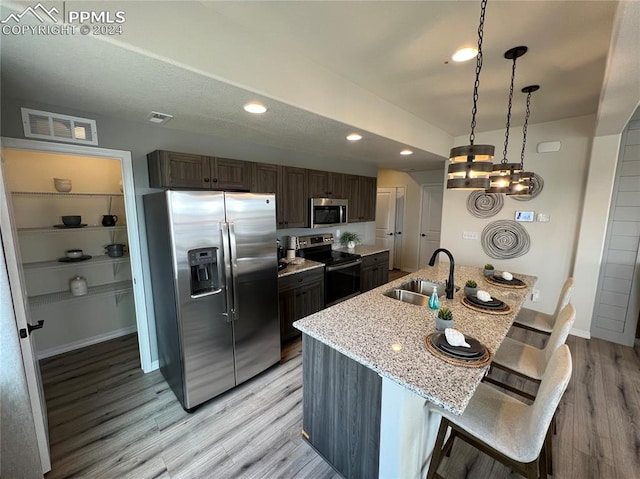 kitchen featuring pendant lighting, a breakfast bar area, light hardwood / wood-style flooring, sink, and stainless steel appliances