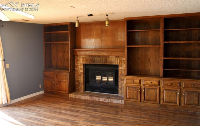 unfurnished living room featuring hardwood / wood-style floors, a fireplace, and a textured ceiling