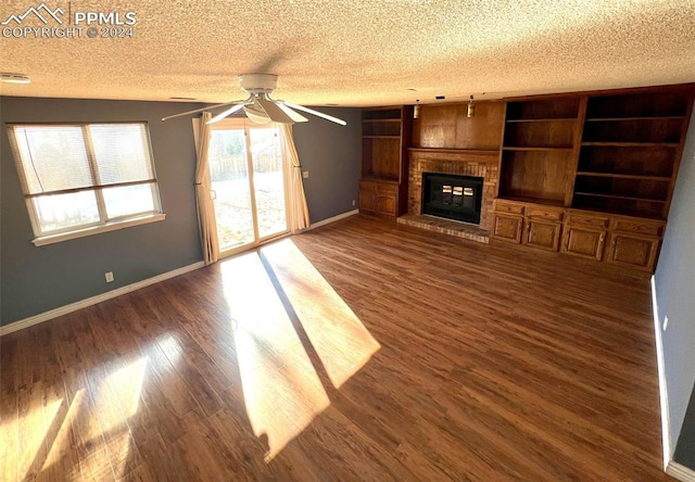 unfurnished living room featuring a fireplace, dark wood-type flooring, a textured ceiling, and ceiling fan