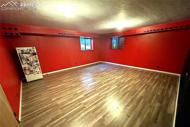 spare room featuring wood-type flooring and a textured ceiling