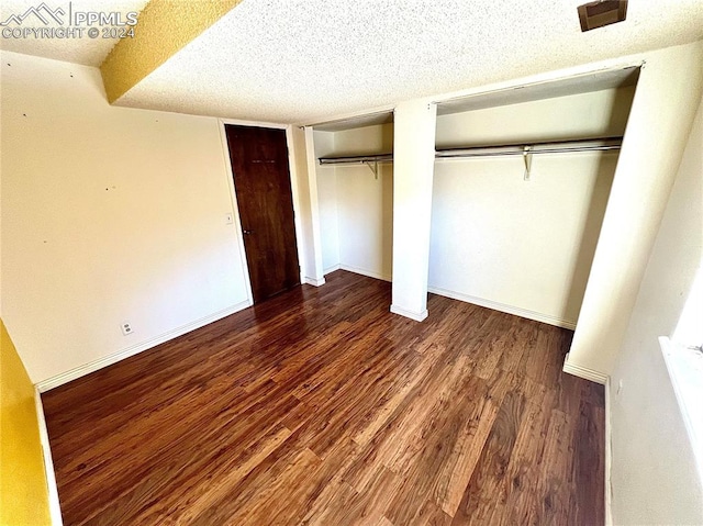 unfurnished bedroom with dark wood-type flooring and a textured ceiling