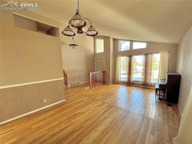 unfurnished living room featuring wood-type flooring, a textured ceiling, and lofted ceiling