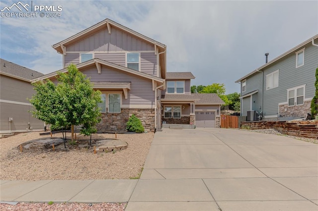 craftsman inspired home featuring central AC unit and a garage