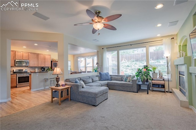 living room featuring ceiling fan with notable chandelier and light hardwood / wood-style flooring