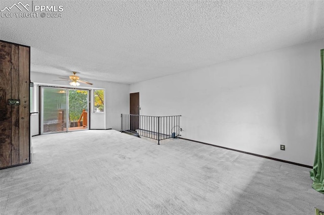 empty room with ceiling fan, a textured ceiling, and light colored carpet