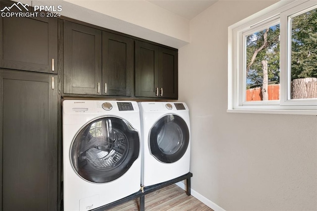 laundry area with separate washer and dryer, light hardwood / wood-style floors, and cabinets