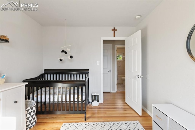 bedroom with a nursery area and light wood-type flooring