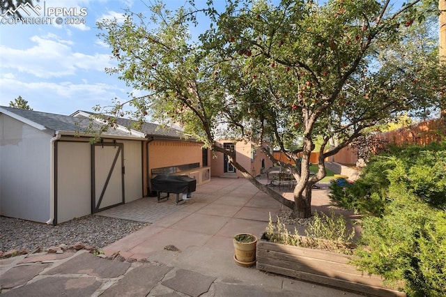 view of side of property with a storage unit and a patio area