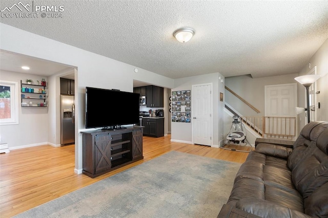 living room featuring a baseboard heating unit, light hardwood / wood-style floors, and a textured ceiling