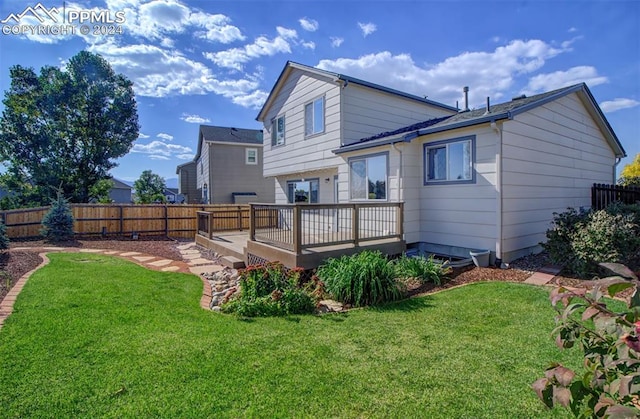 rear view of house featuring a wooden deck and a lawn