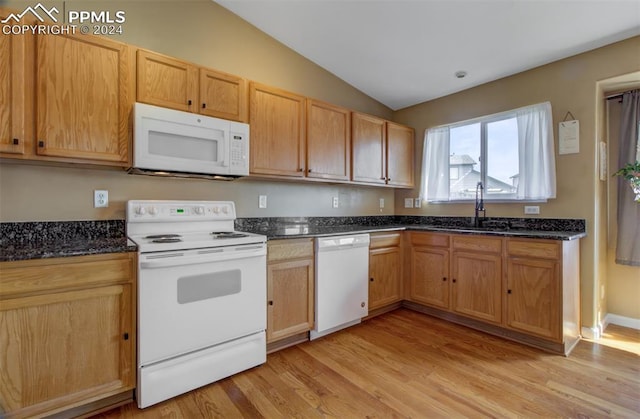 kitchen featuring light hardwood / wood-style floors, white appliances, dark stone counters, vaulted ceiling, and sink