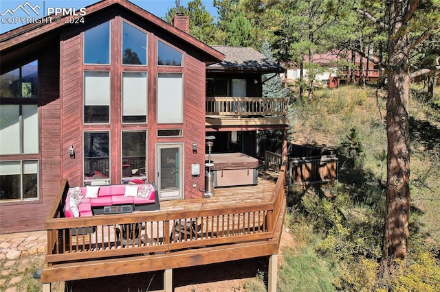 back of property featuring a balcony, an outdoor hangout area, and a hot tub