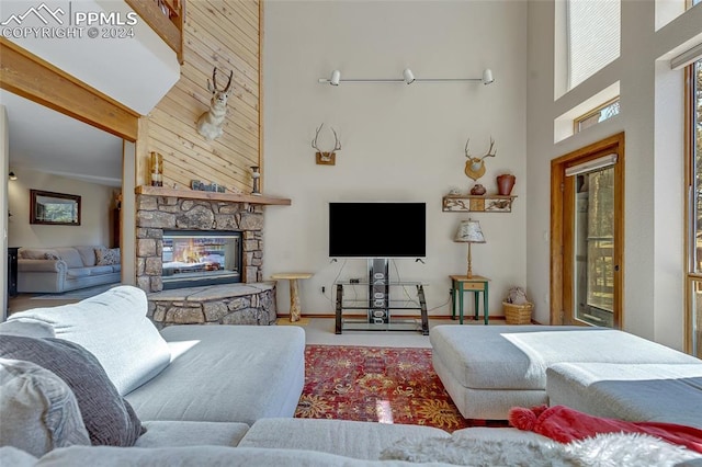 living room with high vaulted ceiling, a stone fireplace, and beamed ceiling