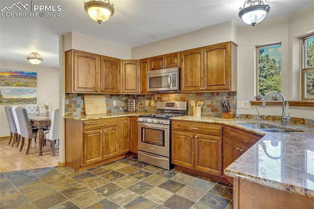 kitchen featuring decorative backsplash, appliances with stainless steel finishes, sink, and light stone counters