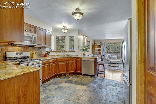 kitchen featuring a textured ceiling, appliances with stainless steel finishes, backsplash, and sink