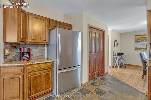 kitchen featuring backsplash, stainless steel refrigerator, dark hardwood / wood-style flooring, and light stone counters