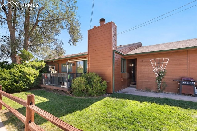 view of front of property with a wooden deck and a front lawn