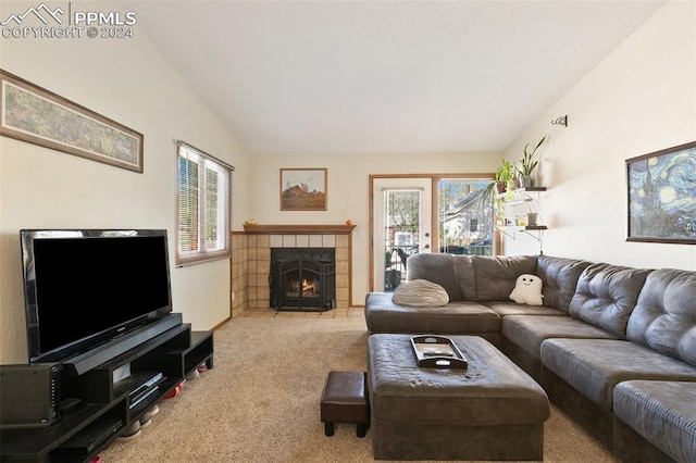 carpeted living room featuring a wealth of natural light, lofted ceiling, and a tiled fireplace