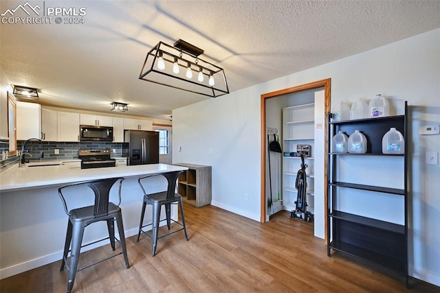 kitchen featuring light hardwood / wood-style flooring, a kitchen breakfast bar, stainless steel appliances, kitchen peninsula, and white cabinetry