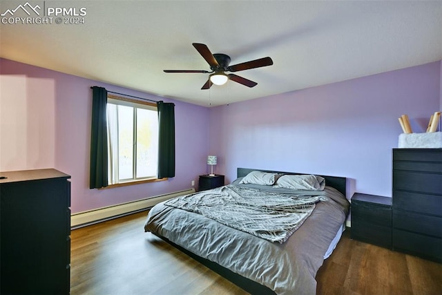 bedroom featuring baseboard heating, hardwood / wood-style flooring, and ceiling fan