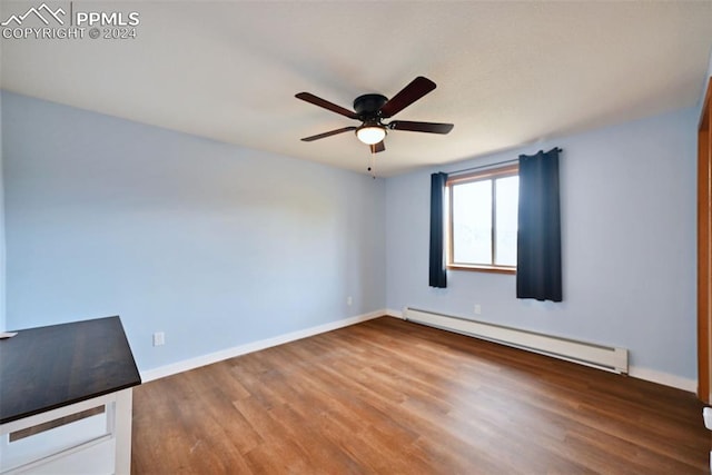 empty room featuring hardwood / wood-style floors, a baseboard heating unit, and ceiling fan