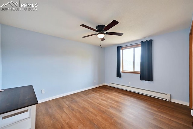 unfurnished room with ceiling fan, a baseboard heating unit, and wood-type flooring