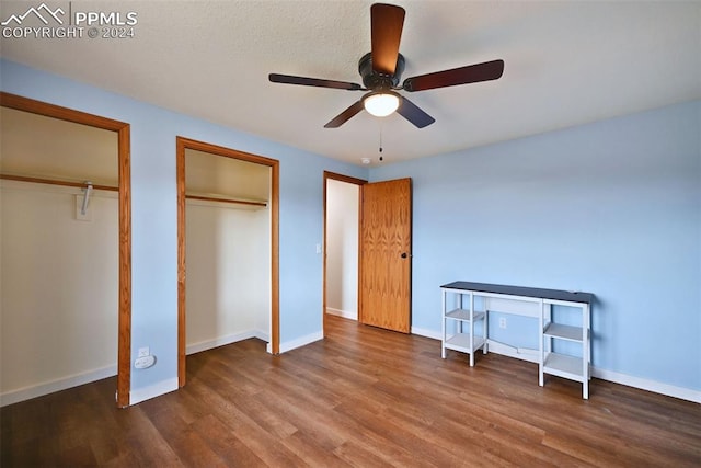 bedroom with ceiling fan, multiple closets, and dark hardwood / wood-style flooring