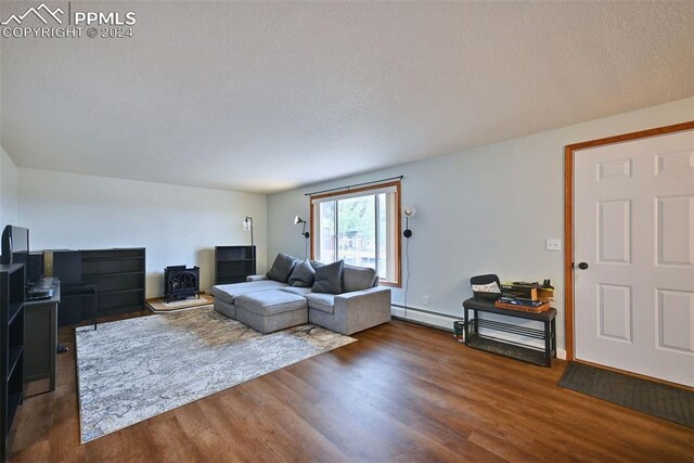 living room featuring a textured ceiling, baseboard heating, and dark hardwood / wood-style flooring