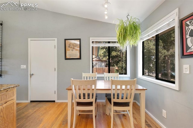 dining room featuring a wealth of natural light, lofted ceiling, and light hardwood / wood-style floors