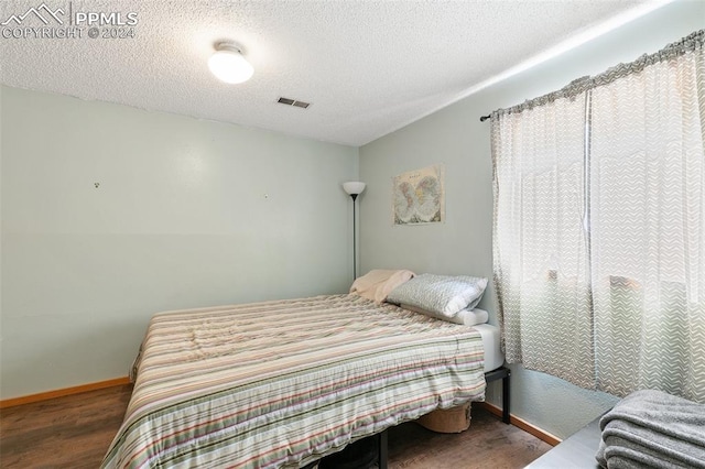 bedroom featuring a textured ceiling and dark hardwood / wood-style floors