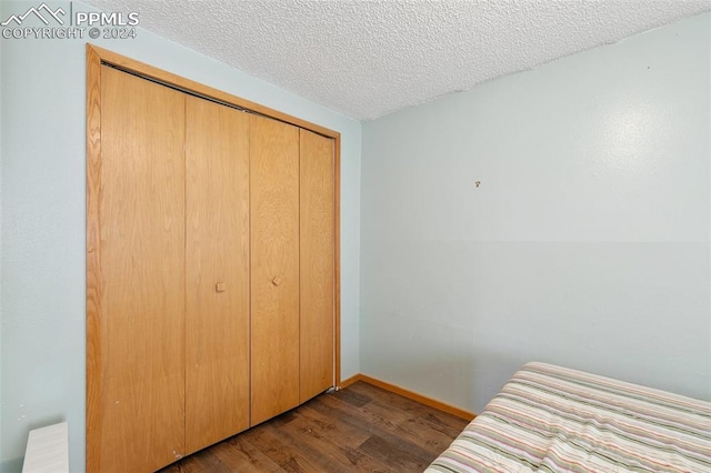 bedroom featuring a textured ceiling, dark hardwood / wood-style floors, and a closet