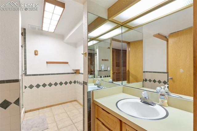 bathroom with vanity, tile walls, a shower with shower door, and tile patterned floors