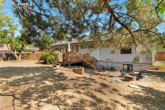 back of property featuring a wooden deck and a fire pit