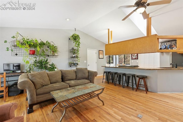 living room featuring ceiling fan, sink, light wood-type flooring, and vaulted ceiling