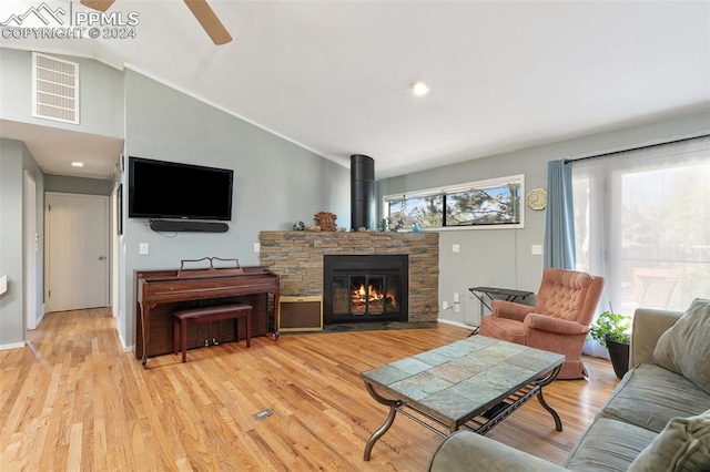 living room with ceiling fan, light hardwood / wood-style flooring, a fireplace, and vaulted ceiling