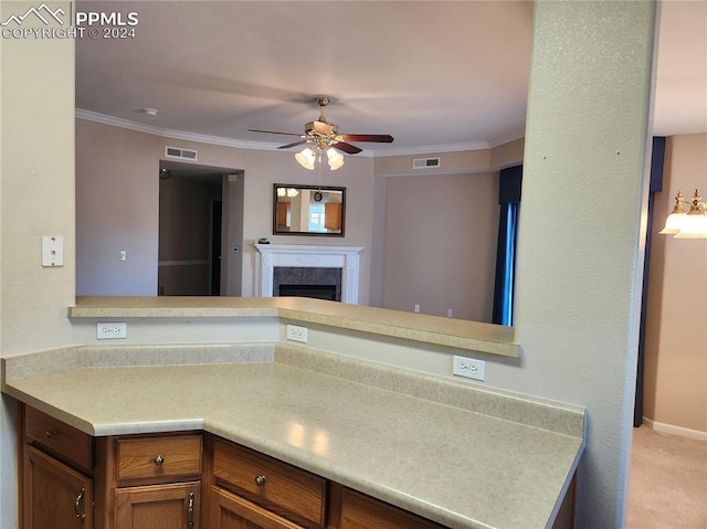 kitchen featuring crown molding, a high end fireplace, light colored carpet, and kitchen peninsula