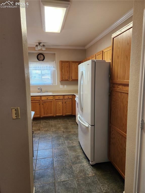 kitchen featuring white refrigerator, crown molding, range, and sink