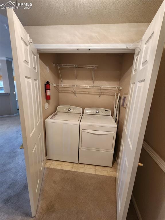 laundry area featuring separate washer and dryer, a textured ceiling, and light tile patterned floors