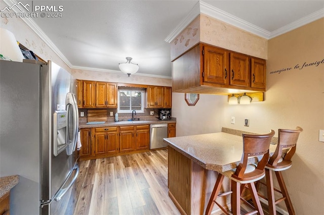 kitchen featuring light wood-type flooring, sink, stainless steel appliances, kitchen peninsula, and ornamental molding