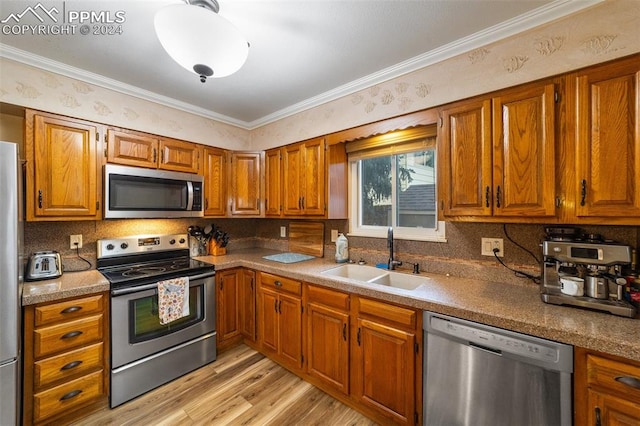 kitchen with light hardwood / wood-style floors, ornamental molding, stainless steel appliances, and sink