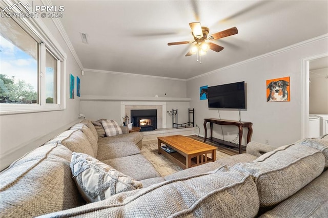 living room with washer and dryer, wood-type flooring, crown molding, and ceiling fan