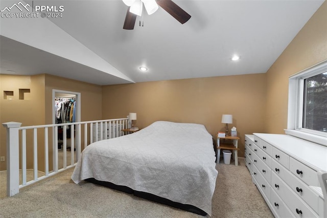 bedroom with ceiling fan, a closet, a spacious closet, light carpet, and vaulted ceiling