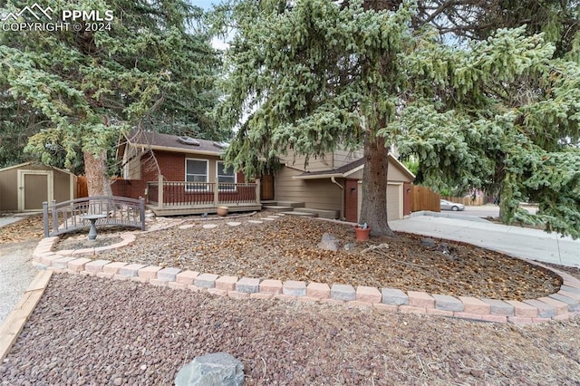 view of front of property with a wooden deck, a storage shed, and a garage