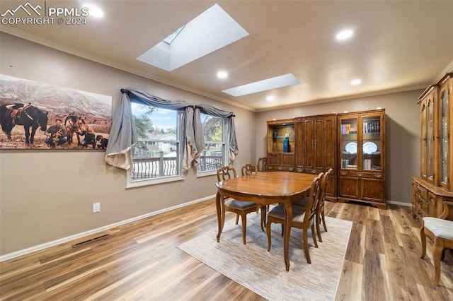 dining area featuring wood-type flooring, crown molding, and a skylight