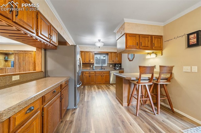 kitchen with ornamental molding, sink, stainless steel dishwasher, light hardwood / wood-style flooring, and a kitchen bar