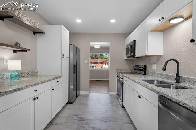 kitchen with light stone counters, stainless steel appliances, sink, and white cabinetry