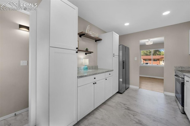 kitchen with stainless steel range with electric cooktop, white cabinets, and light stone counters