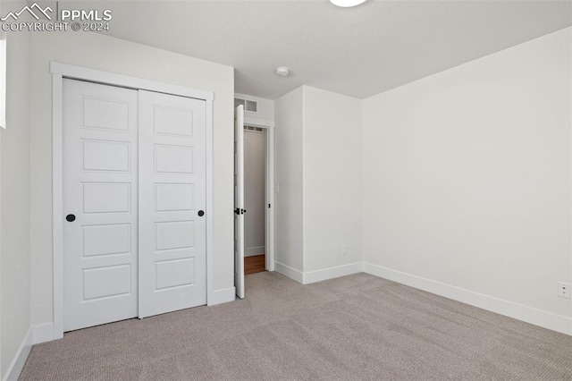 unfurnished bedroom with a closet and light carpet