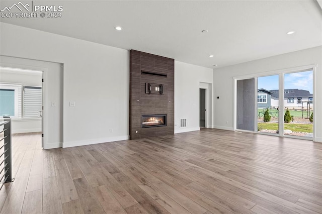 unfurnished living room featuring light hardwood / wood-style floors and a tile fireplace