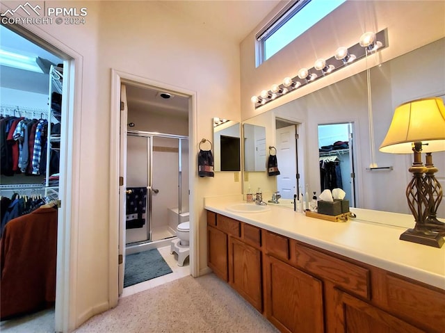 bathroom featuring vanity, a shower with door, and toilet